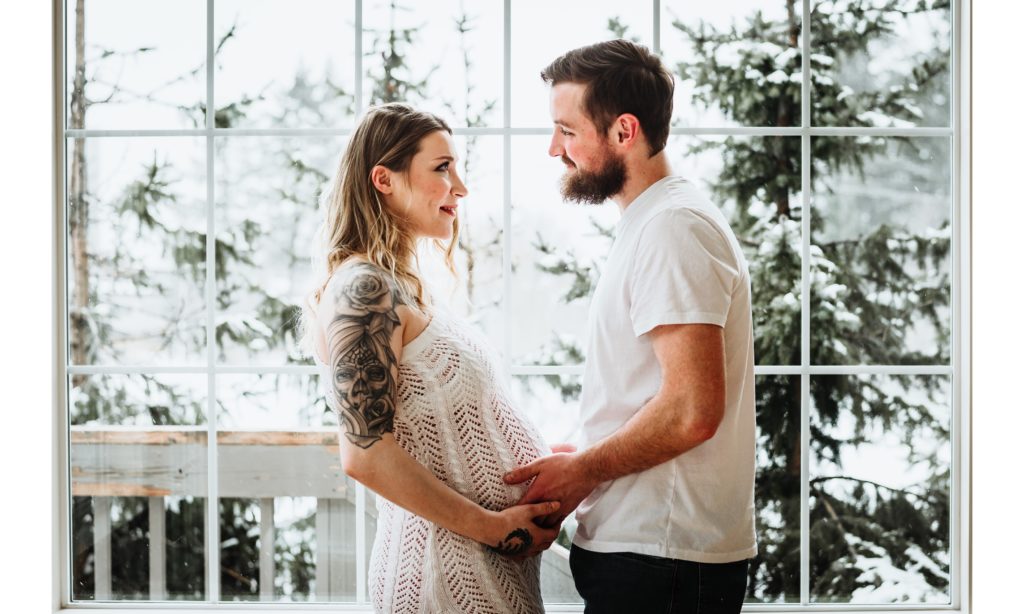 maternity couple in front of window in winter