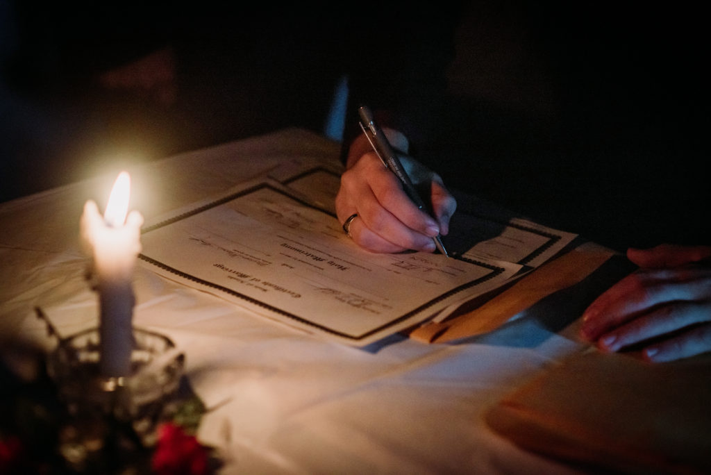 signing a marriage license by candlelight after a cabin elopement in juneau alaska