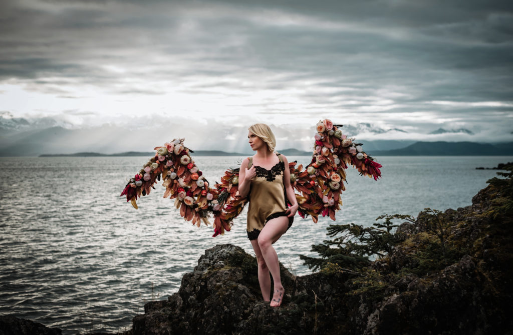 outdoor boudoir with woman wearing flower wings against epic alaska backdrop