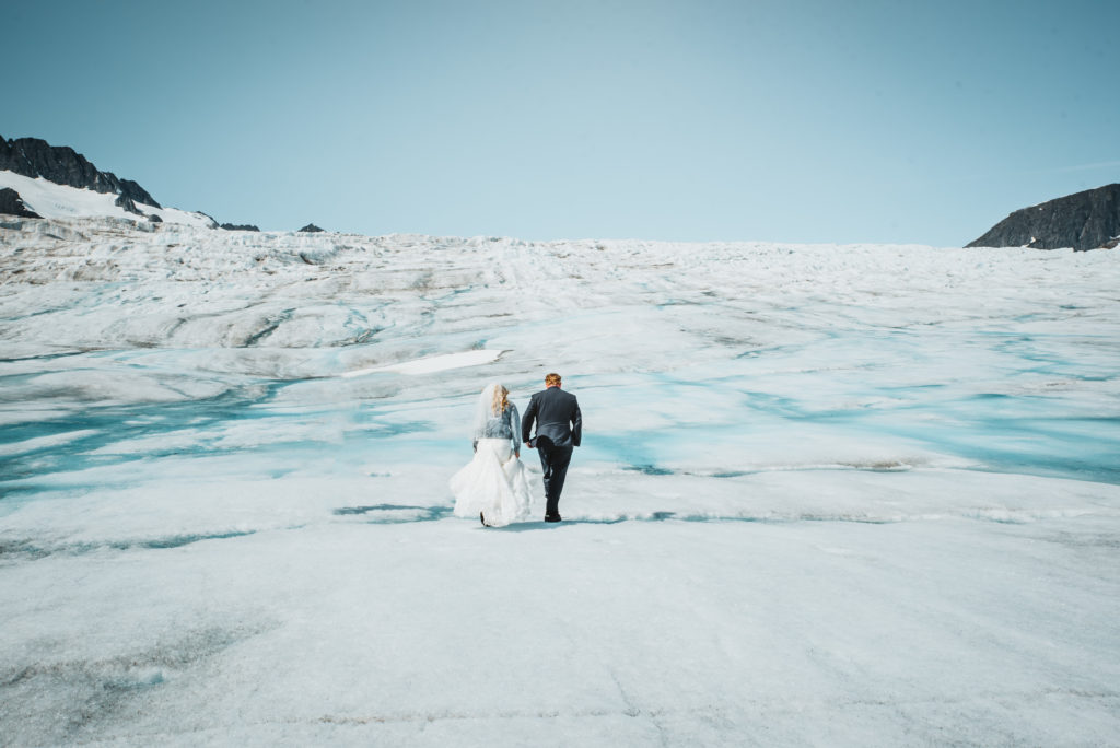 bride and groom walking across a landscape of ice on top of an alaskan glacier 