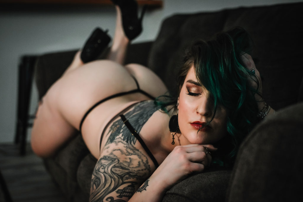 alternative woman with green hair and tattoos posing for boudoir shoot