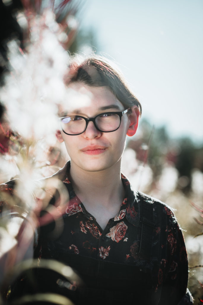 senior session in a fireweed field with bright sun and wispy white fireweed