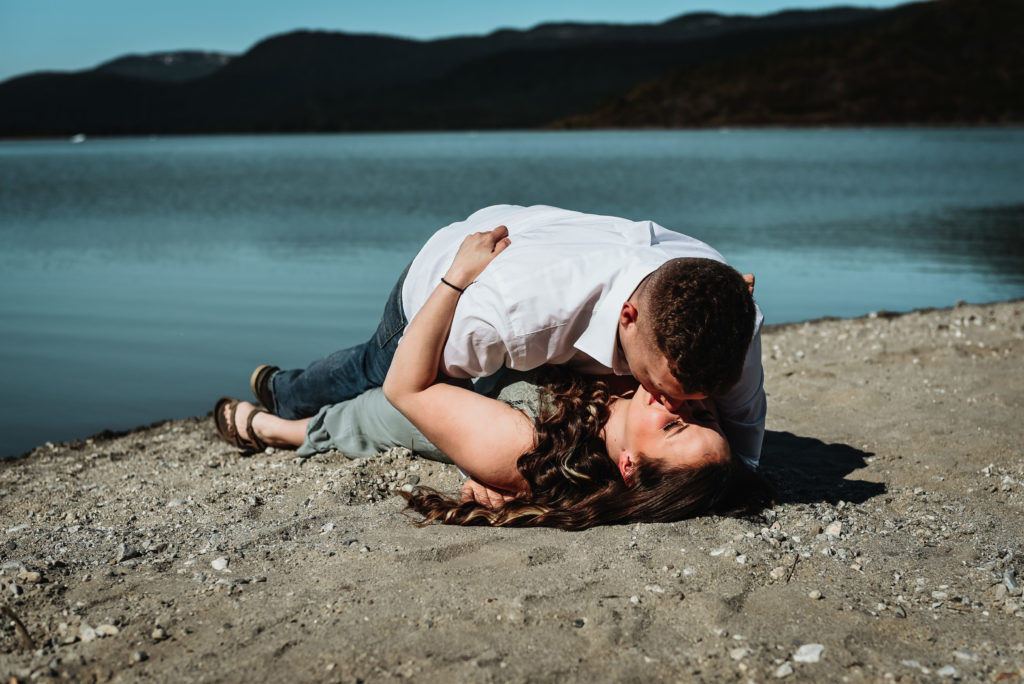 couple rolling around in sand kissing