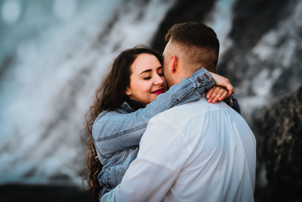 couple embracing in front of nugget falls waterfall in juneau alaska