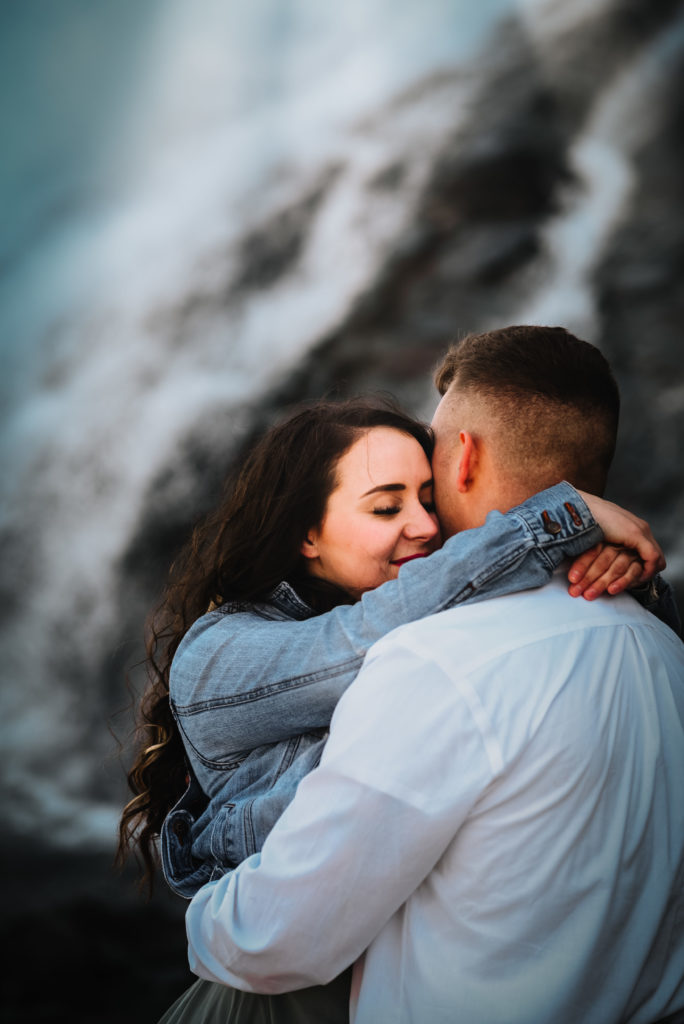 couple hugging in front of waterfall