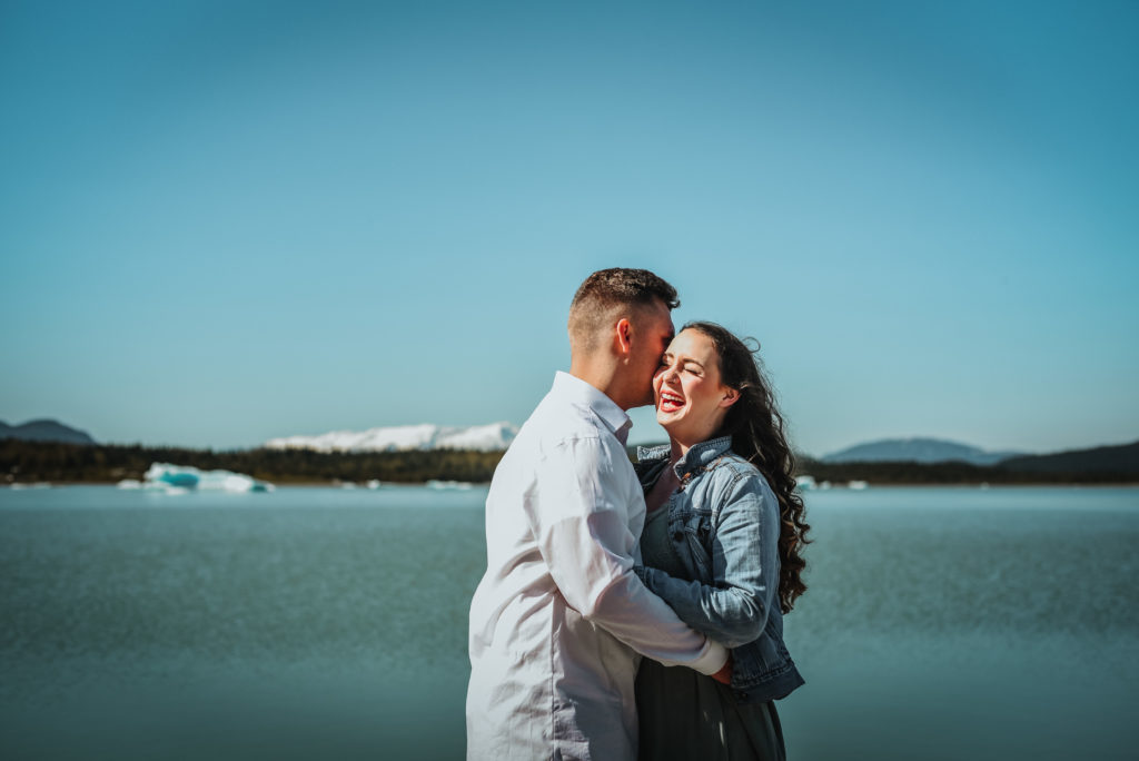 couple's session with woman laughing in front of icebergs in juneau alaska