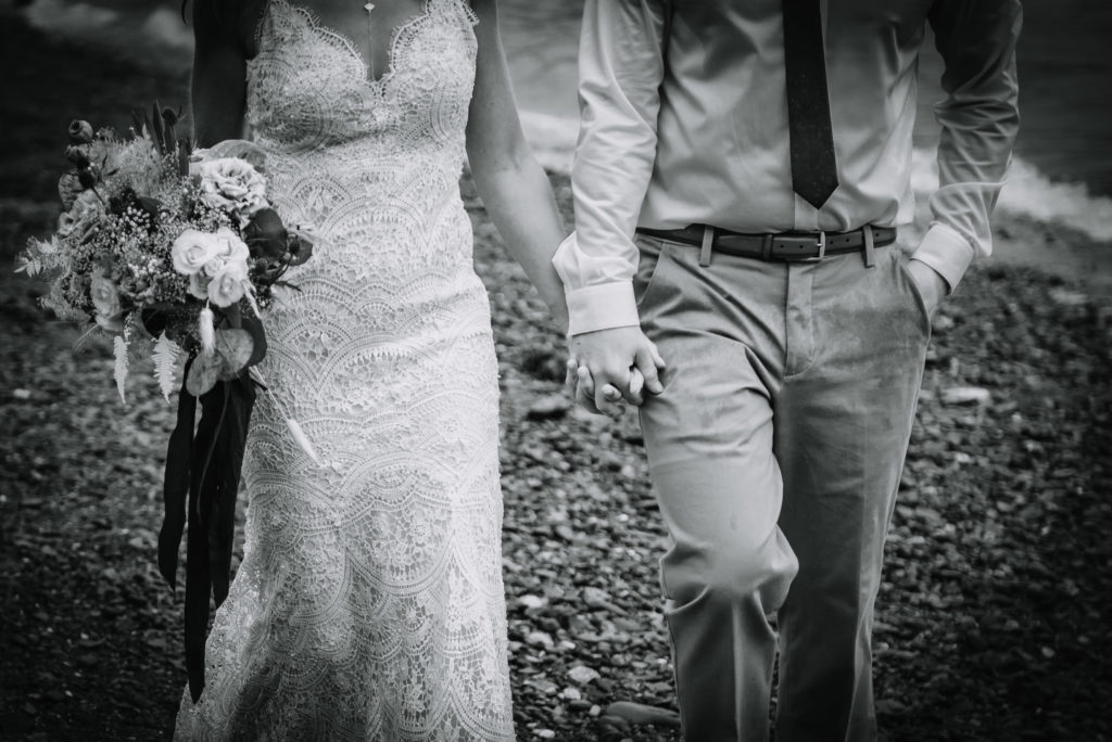 bride and groom hold hands in the pouring rain