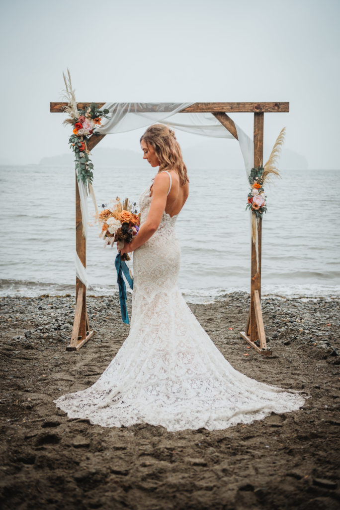 Alaska beach wedding bridal portrait of bride and her wedding dress in the rain