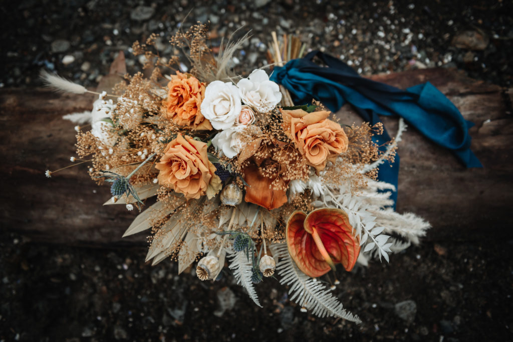 blue white and orange boho wedding bouquet in the sand