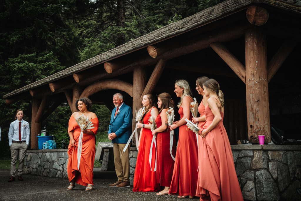 bridesmaids lined up in front of alaska beach cabin