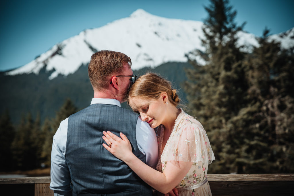 bride hugging groom under mountain at mendenhall glacier