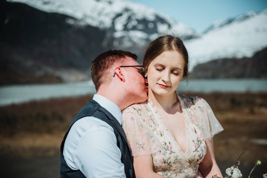 groom kissing brides neck in front of mendenhall glacier