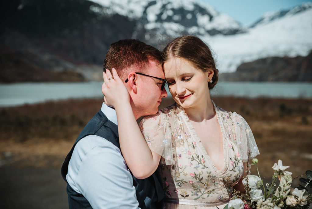 bride and groom eyes closed in front of mendenhall glacier