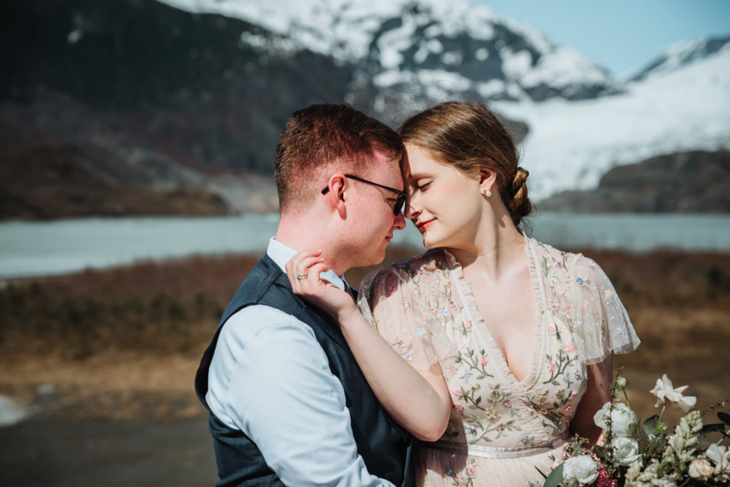bride and groom almost kissing in front of mendenhall glacier