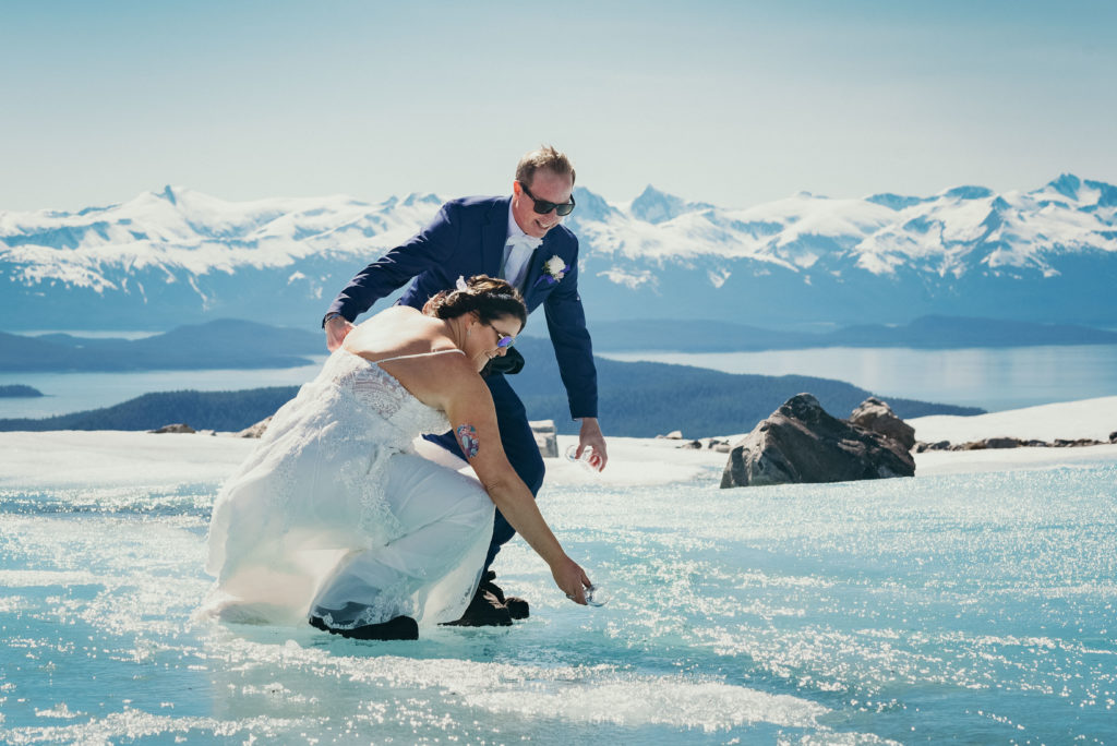 bride and groom collecting glacier water from glacier stream