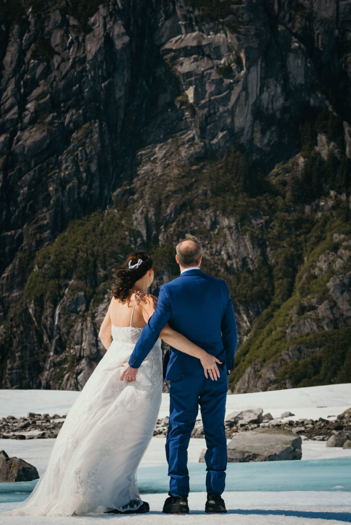 bride and groom touching butts on glacier