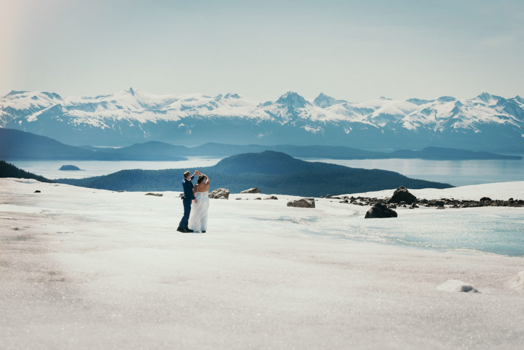 bride and groom dancing on juneau glacier with epic background