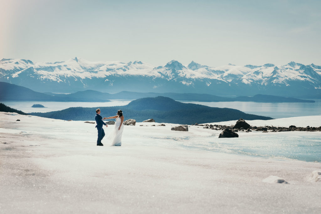 bride and groom holding hands walking on glacier with gorgeous background