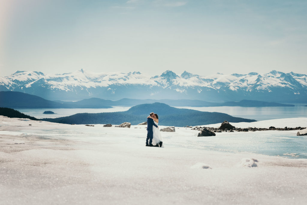 bride and groom kissing on juneau glacier with beautiful background