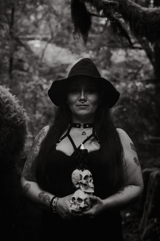 woman dressed as witch holding skulls at styled shoot