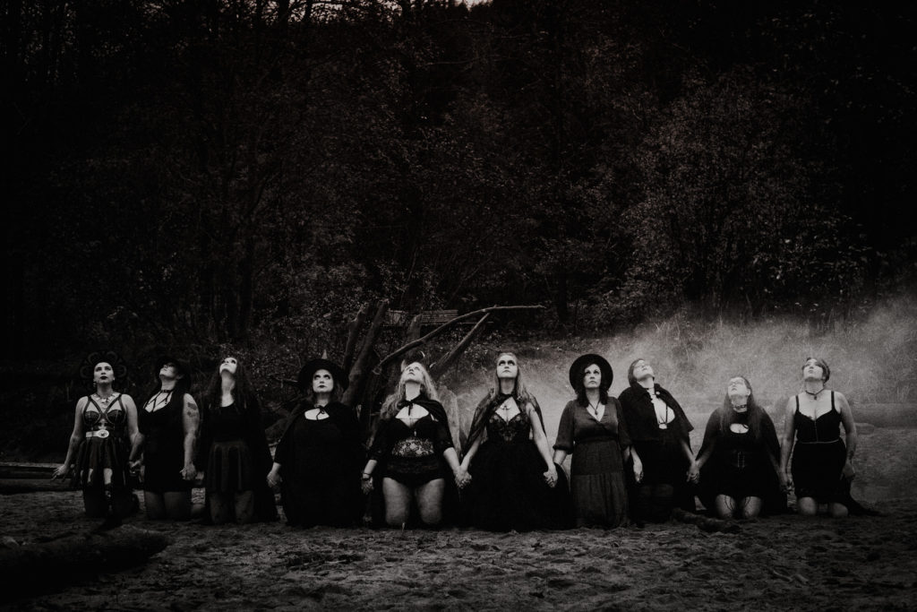 witch coven kneeling on beach with smoke 