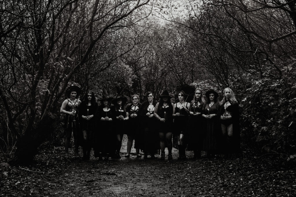 black and white photo of witches in woods holding candles