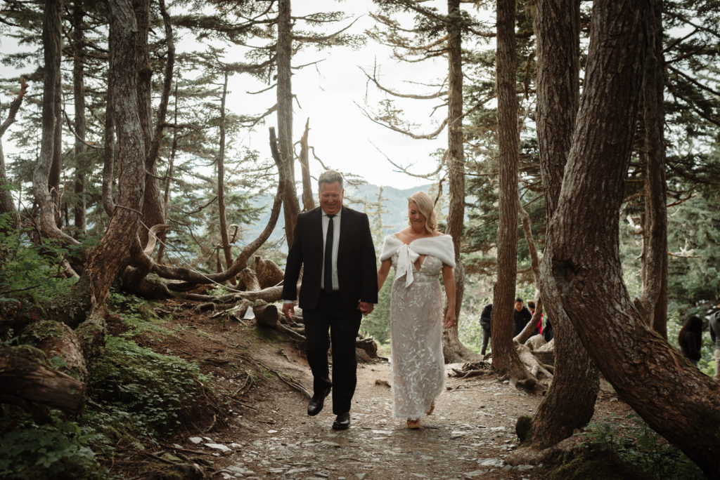 bride and groom walking through twisting trees on mount roberts