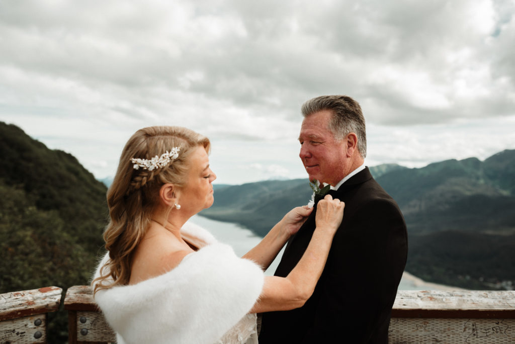 bride securing grooms Boutonnière on Alaska mountaintop 