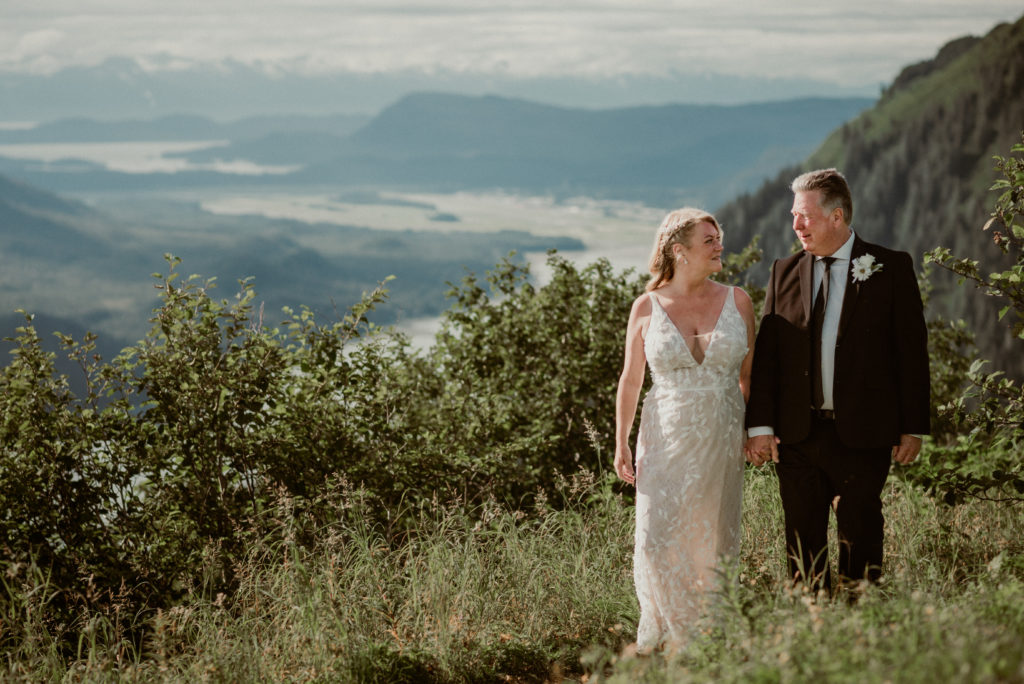 bride and groom walking along mountaintop in juneau alaska