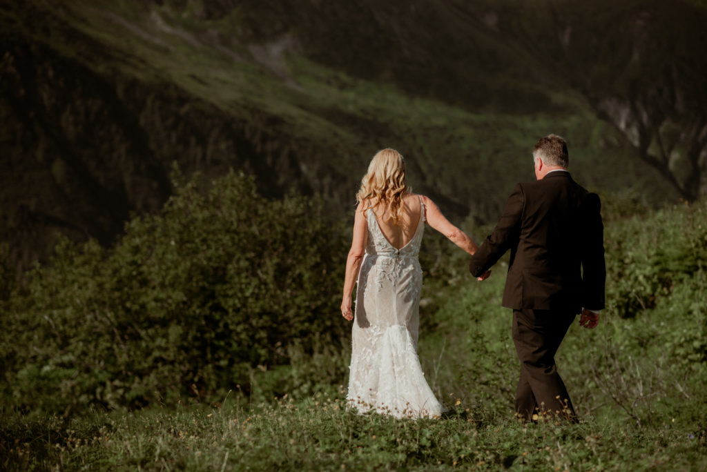 bride and groom walking along the hills of a mountaintop in juneau alaska