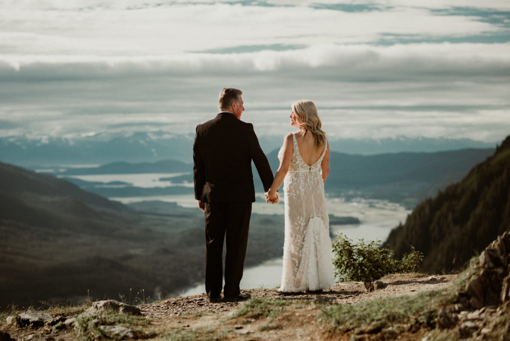 bride and groom holding hands in front of epic view of the gastineau channel in juneau alaska