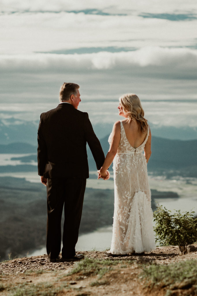 bride and groom holding hands during a moment on top of mount roberts in juneau alaska
