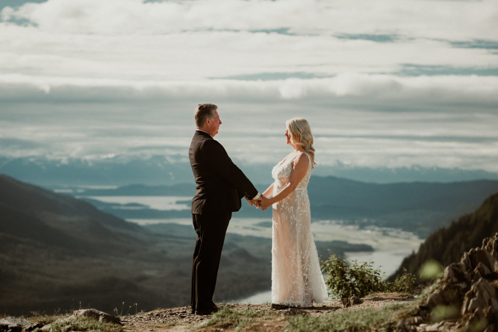 bride and groom saying vows in front of epic view on top of mount roberts in juneau alaska
