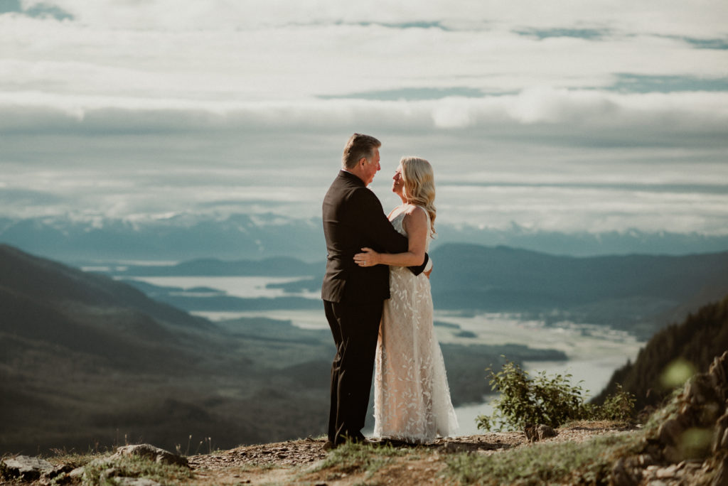 bride and groom holding each other in front of epic view of channel in juneau alaska