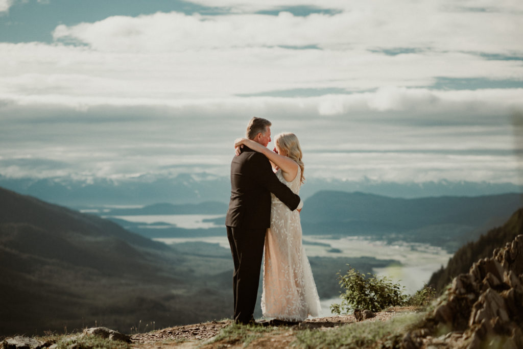 bride and groom slow dancing in front of epic view of channel in front of juneau alaska