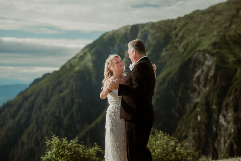 bride and broom dancing and laughing on alaska mountaintop