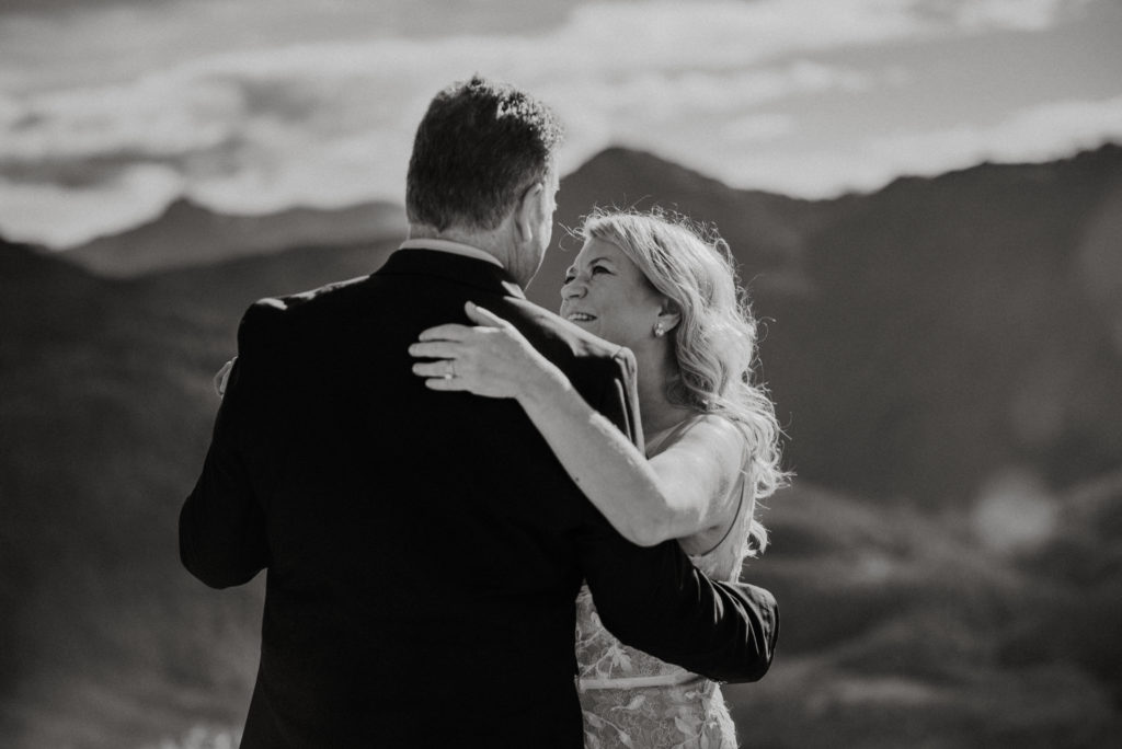black and white photo of bride and groom slow dancing on alaska mountaintop