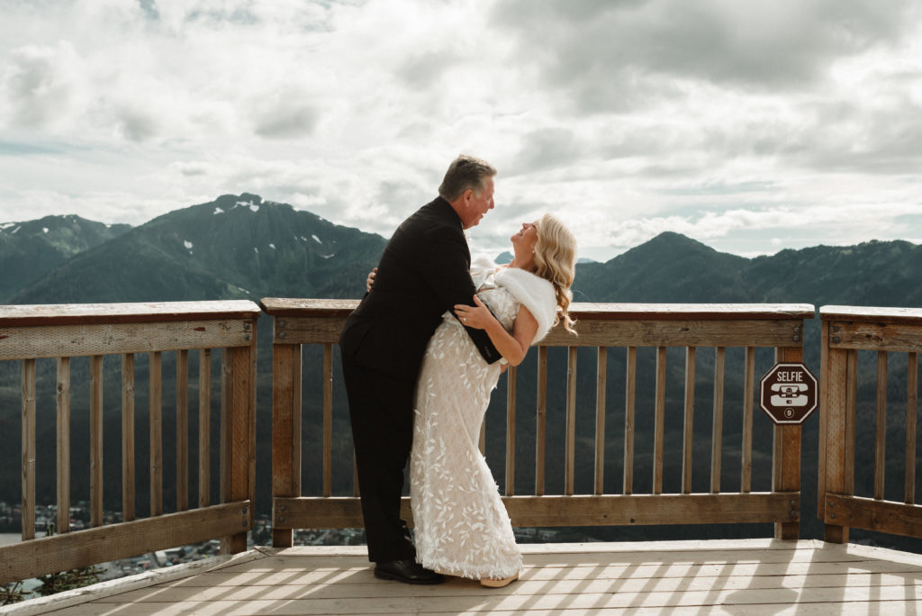 alaska mountaintop elopement groom dips bride while they laugh