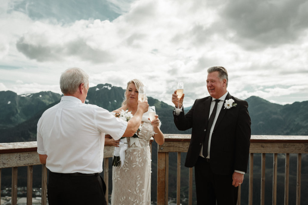 bride and groom have a champagne toast with their officient after eloping on mount roberts