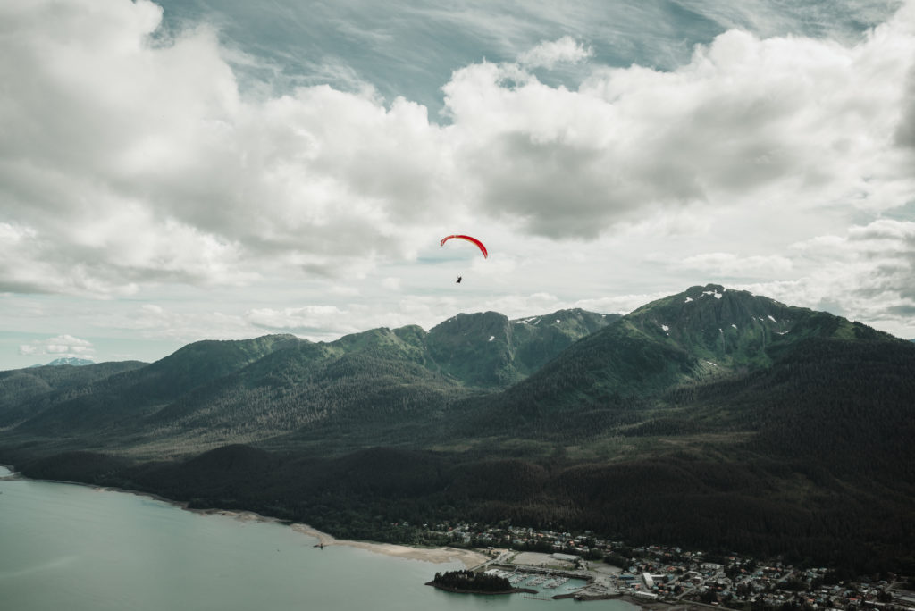 Paraglider soaring over gastineau channel and mountantops in juneau alaska