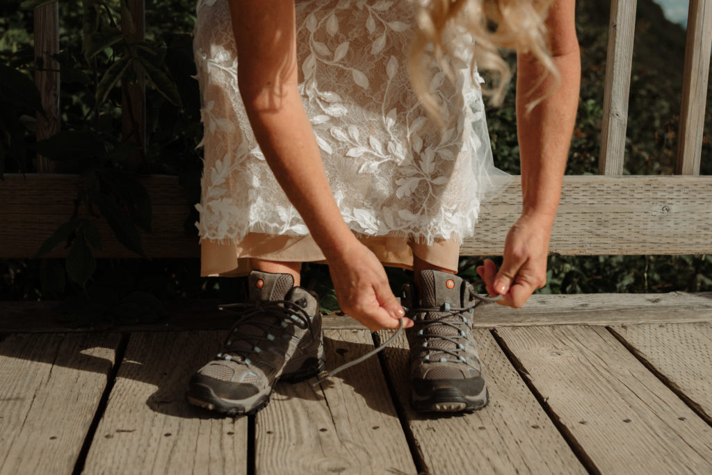 bride tying her hiking boots during alaska mountaintop elopement