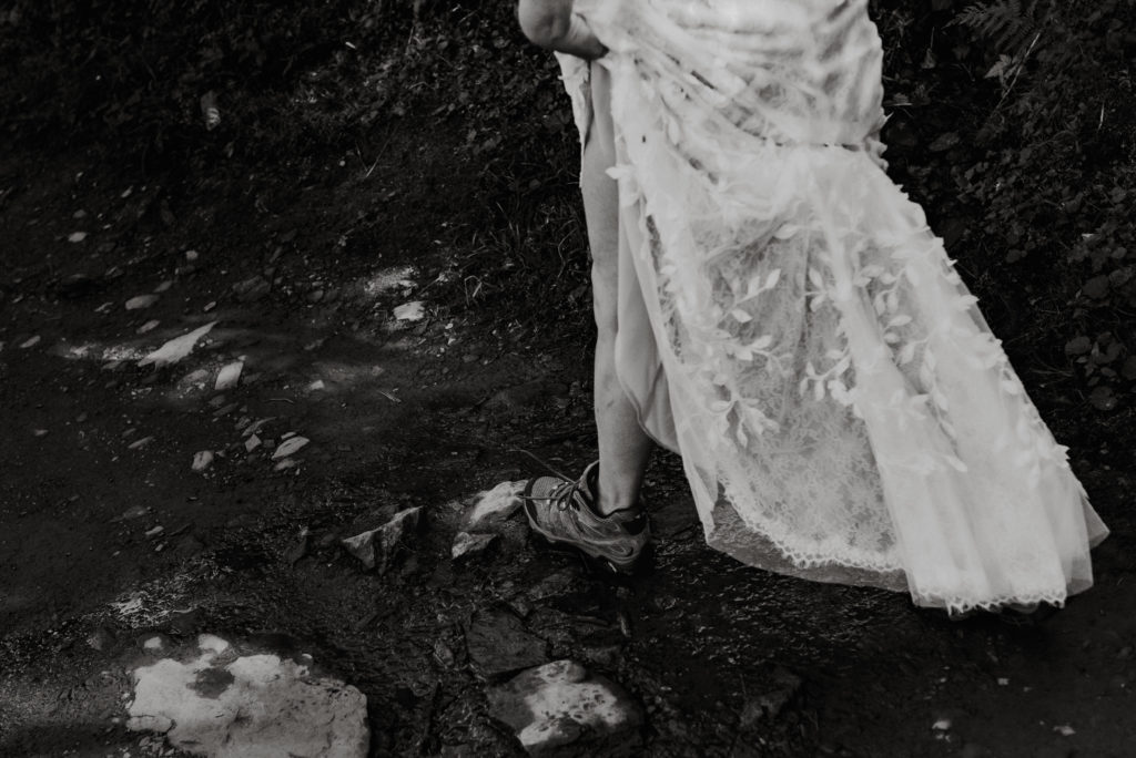 bride stepping over puddles in hiking boots during alaska mountaintop elopement