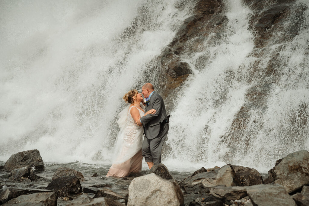 Couple at base of Nugget Falls Waterfall Mendenhall Lake Juneau Alaska