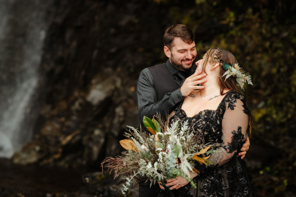 Dark and moody waterfall elopement with bride in a black wedding dress