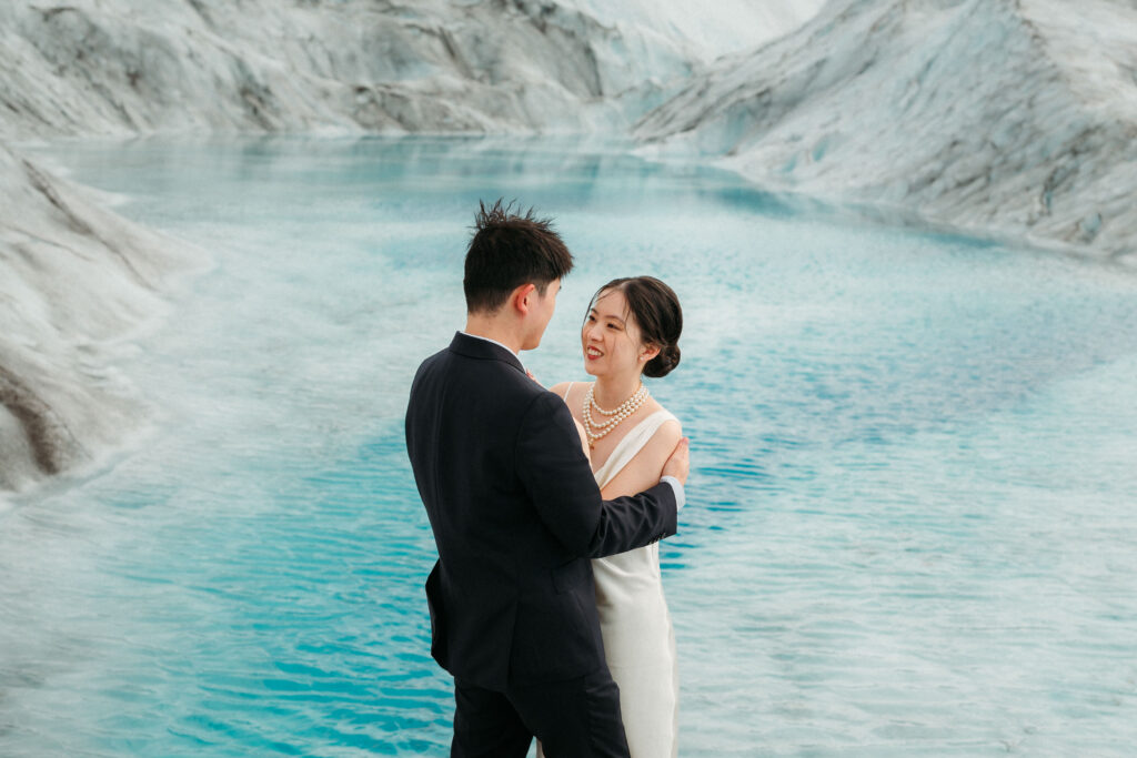 bride and groom in front of blue ice pool on knik glacier