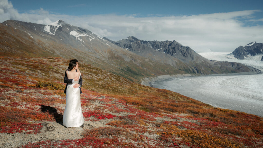 bride and groom on mountaintop looking over the knik glacier
